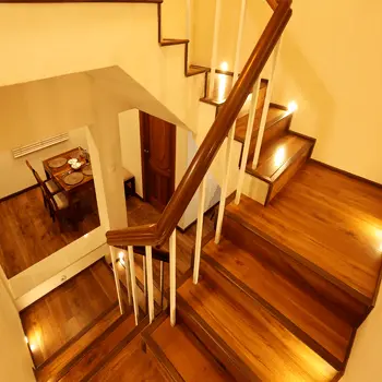 Wooden staircase with a metal handrail and illuminated steps