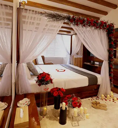 Four-poster bed with sheer curtains and red floral decorations