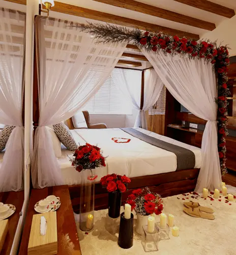 Four-poster bed with sheer curtains and red floral decorations